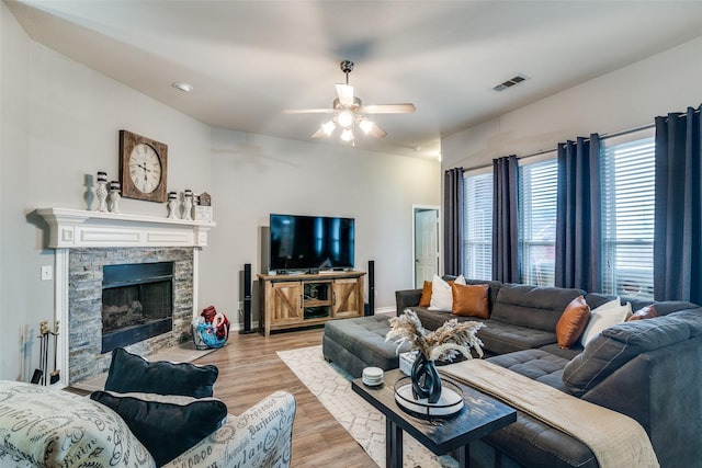 living room featuring a fireplace, ceiling fan, and light hardwood / wood-style flooring