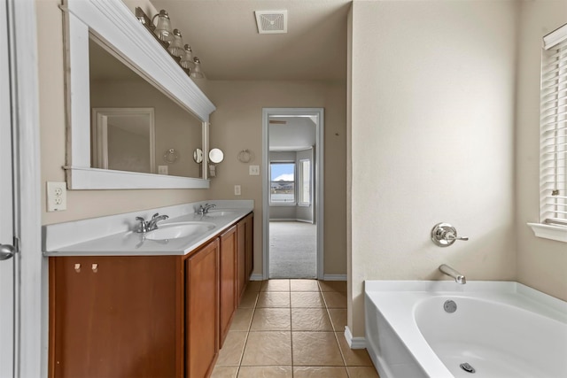 bathroom featuring tile patterned flooring, vanity, and a tub to relax in