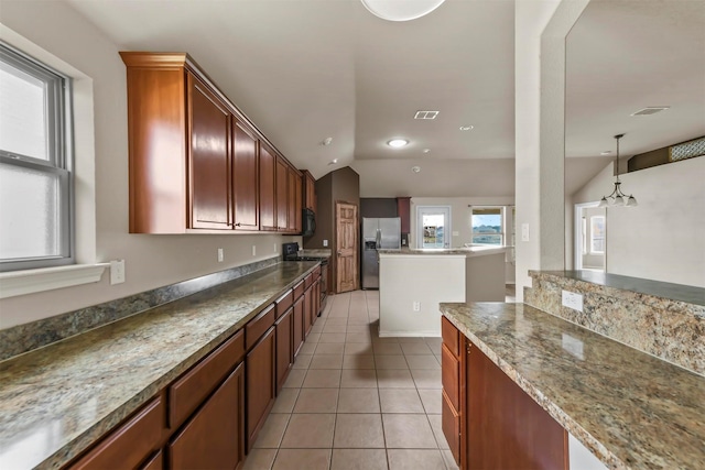 kitchen featuring pendant lighting, light tile patterned floors, lofted ceiling, stainless steel fridge, and stove