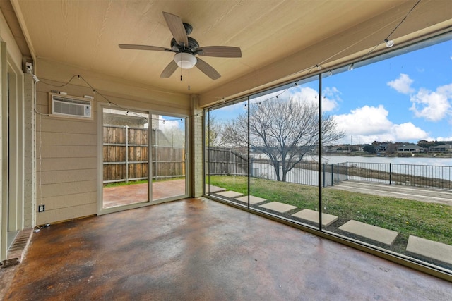 unfurnished sunroom with a water view, a wall mounted air conditioner, and ceiling fan