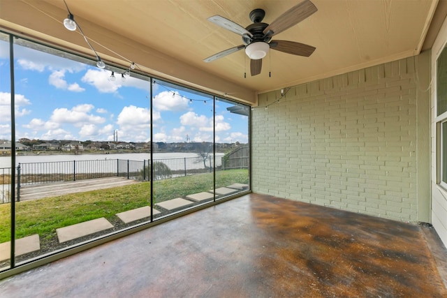 unfurnished sunroom featuring ceiling fan and a water view