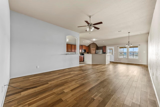 unfurnished living room with vaulted ceiling, dark wood-type flooring, and ceiling fan with notable chandelier