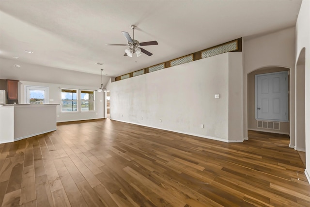 unfurnished living room featuring ceiling fan with notable chandelier and dark hardwood / wood-style floors