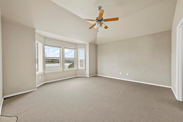 spare room featuring carpet floors, ceiling fan, and vaulted ceiling