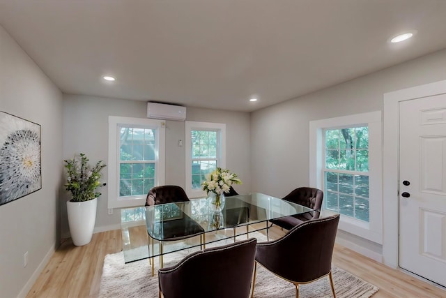 dining space with an AC wall unit and light hardwood / wood-style flooring