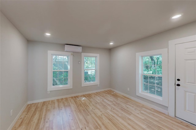 spare room with light hardwood / wood-style floors and a wall unit AC