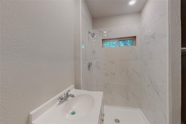 bathroom featuring a tile shower and vanity