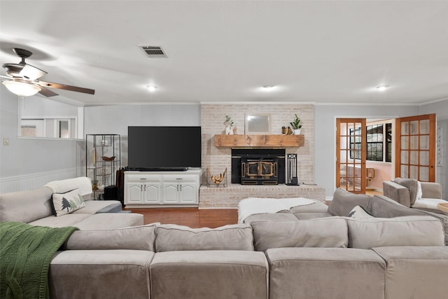 living room featuring a brick fireplace, crown molding, ceiling fan, and light wood-type flooring