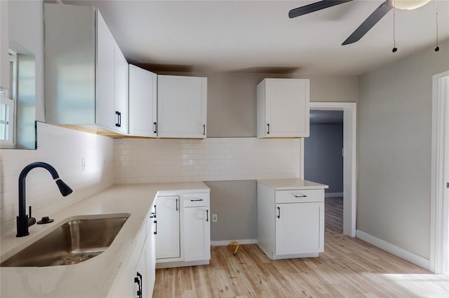 kitchen featuring tasteful backsplash, white cabinetry, sink, ceiling fan, and light hardwood / wood-style floors