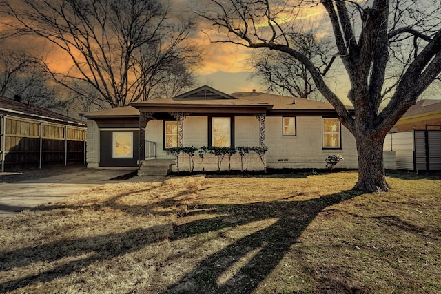 back house at dusk featuring a lawn