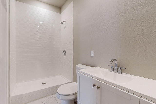 bathroom with tiled shower, vanity, and toilet