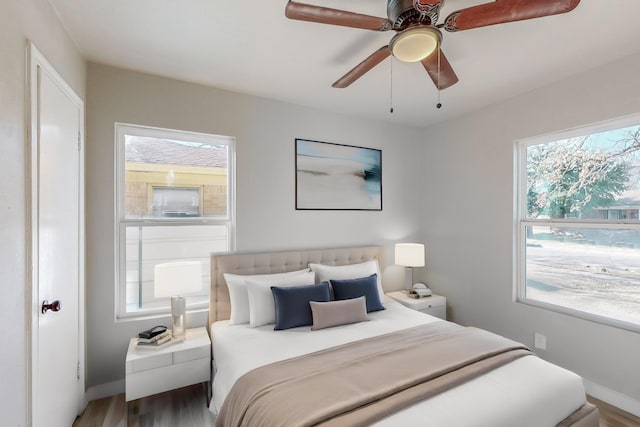 bedroom featuring hardwood / wood-style floors, ceiling fan, and multiple windows