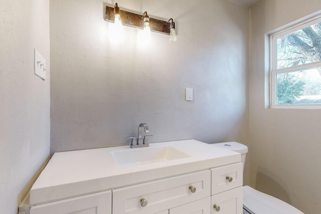 bathroom featuring vanity, a healthy amount of sunlight, and toilet