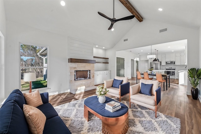 living room with hardwood / wood-style floors, high vaulted ceiling, beamed ceiling, and ceiling fan