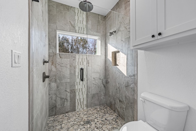 bathroom featuring tiled shower and toilet