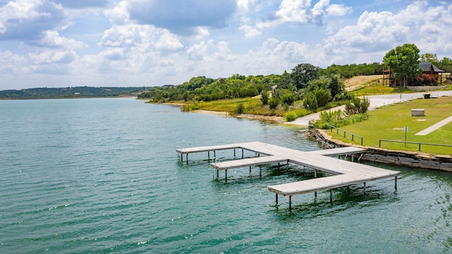 view of dock with a yard and a water view