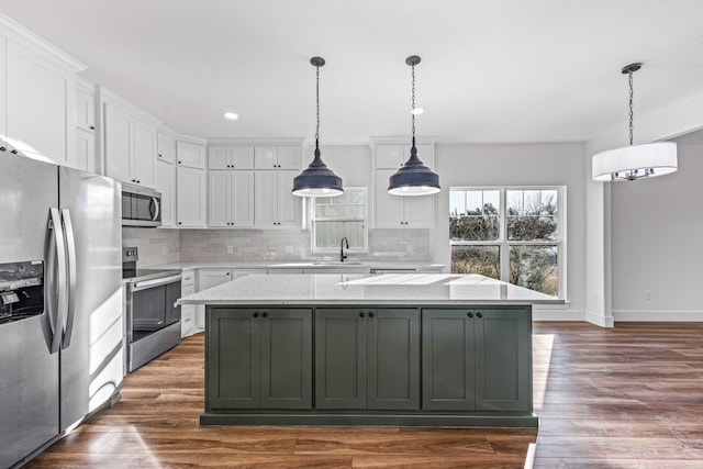 kitchen with white cabinetry, hanging light fixtures, stainless steel appliances, light stone counters, and a kitchen island