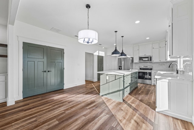 kitchen with pendant lighting, appliances with stainless steel finishes, dark hardwood / wood-style floors, white cabinets, and a kitchen island