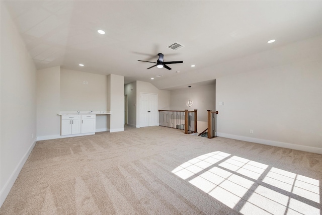 unfurnished living room featuring vaulted ceiling, light colored carpet, and ceiling fan