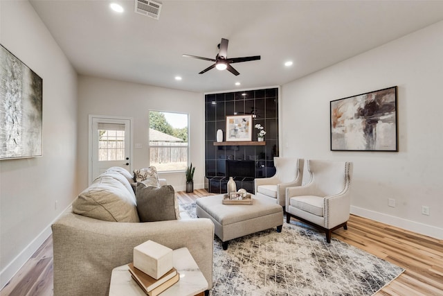 living room with ceiling fan, hardwood / wood-style floors, and a tile fireplace