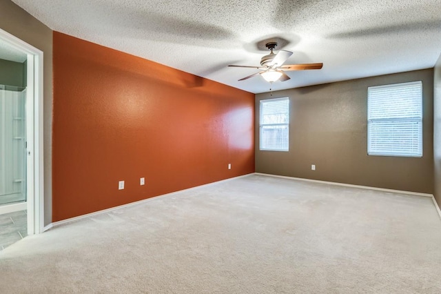 spare room with light colored carpet, a textured ceiling, and ceiling fan