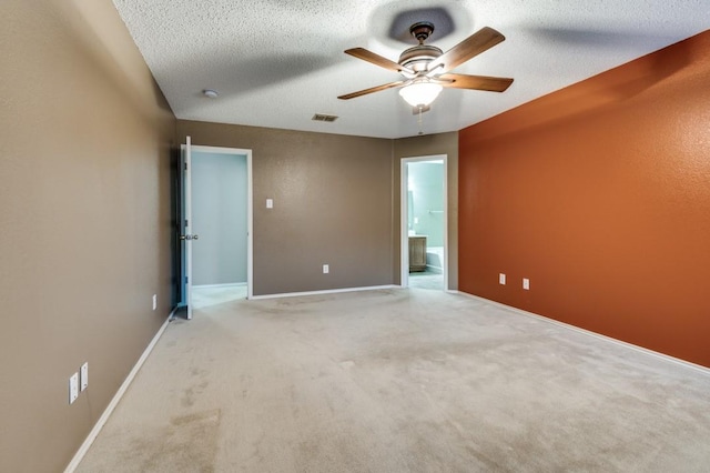 spare room featuring ceiling fan, light colored carpet, and a textured ceiling