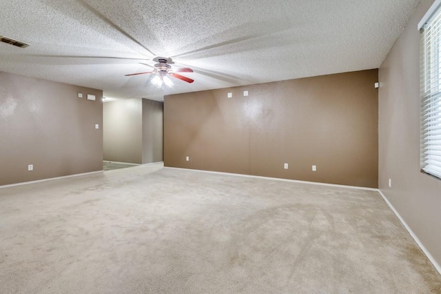 carpeted empty room with ceiling fan and a textured ceiling