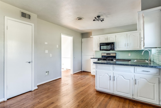 kitchen featuring white cabinets, stainless steel gas range, tasteful backsplash, and sink