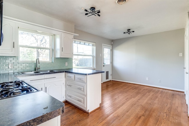 kitchen with sink, light wood-type flooring, white cabinetry, and kitchen peninsula