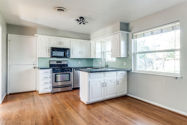 kitchen featuring sink, light hardwood / wood-style flooring, decorative backsplash, appliances with stainless steel finishes, and white cabinetry