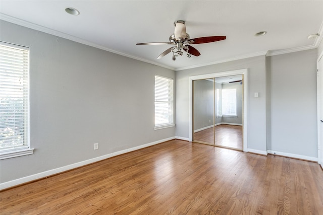 unfurnished bedroom with hardwood / wood-style floors, ceiling fan, ornamental molding, and a closet