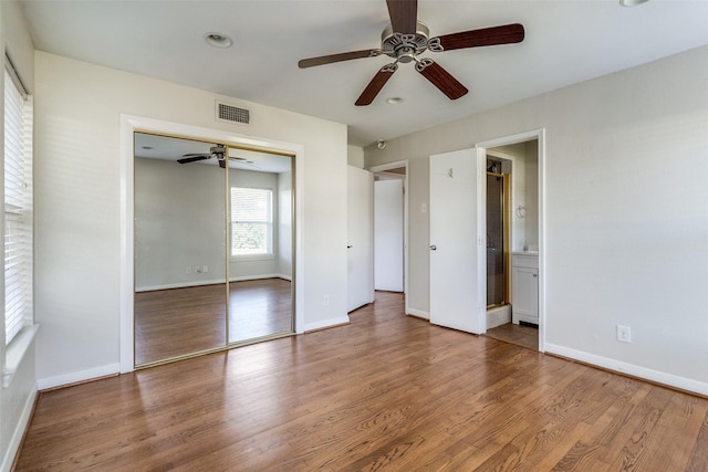 unfurnished bedroom with ensuite bath, ceiling fan, a closet, and wood-type flooring