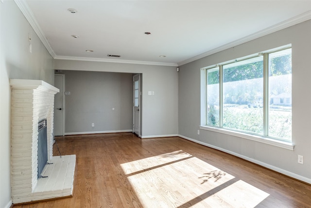 unfurnished living room with crown molding, a wealth of natural light, a fireplace, and light hardwood / wood-style floors