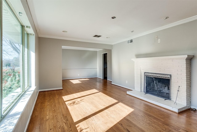 unfurnished living room with hardwood / wood-style floors, ornamental molding, and a brick fireplace