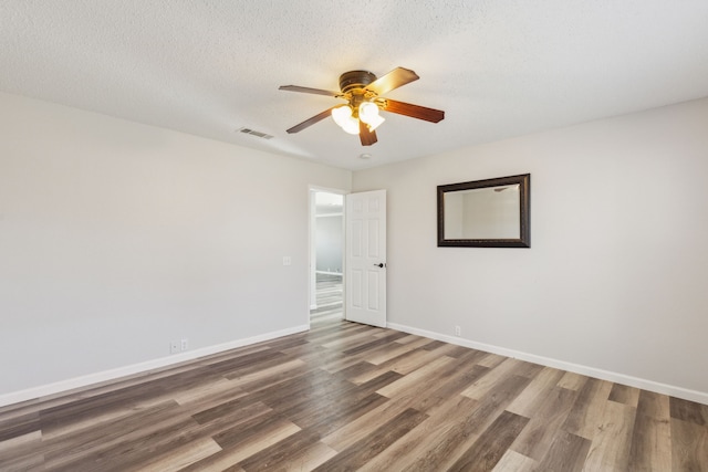 spare room featuring ceiling fan, dark hardwood / wood-style flooring, and a textured ceiling