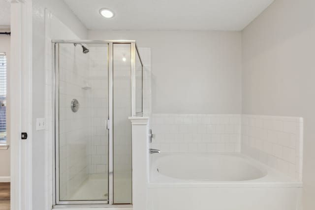 bathroom with a textured ceiling and separate shower and tub