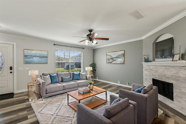 unfurnished living room with hardwood / wood-style flooring, ceiling fan with notable chandelier, a stone fireplace, and crown molding