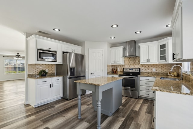 kitchen with appliances with stainless steel finishes, white cabinetry, wall chimney exhaust hood, and sink