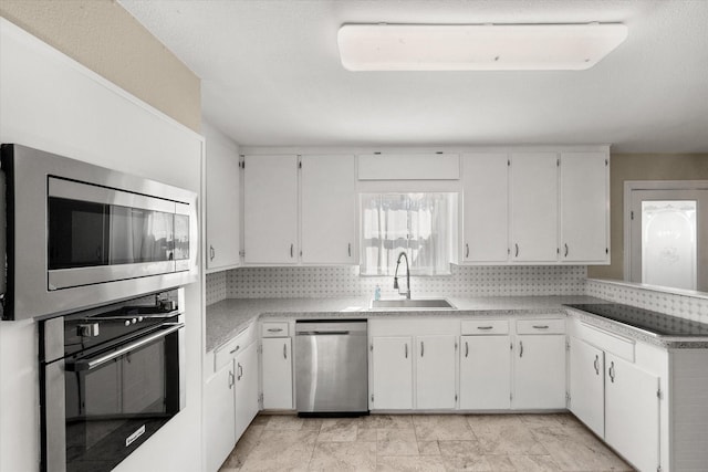 kitchen with white cabinets, appliances with stainless steel finishes, a sink, light countertops, and backsplash