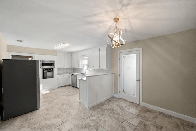 kitchen with pendant lighting, light countertops, appliances with stainless steel finishes, white cabinetry, and a sink