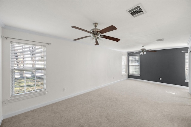 empty room with visible vents, ornamental molding, light carpet, ceiling fan, and baseboards