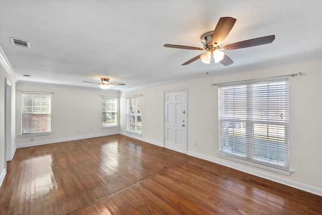 spare room with wood finished floors, visible vents, and crown molding