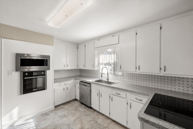 kitchen with light countertops, appliances with stainless steel finishes, a sink, and white cabinetry