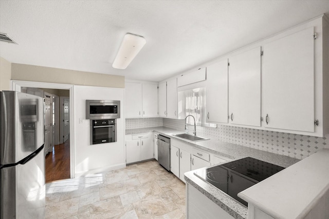 kitchen featuring stainless steel appliances, a sink, visible vents, white cabinetry, and light countertops