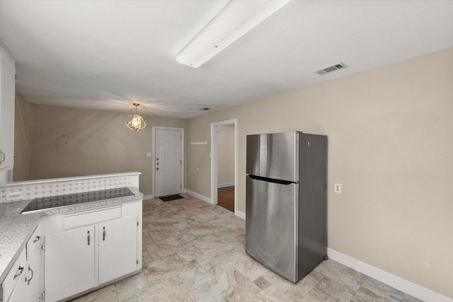 kitchen with visible vents, decorative light fixtures, freestanding refrigerator, light countertops, and white cabinetry