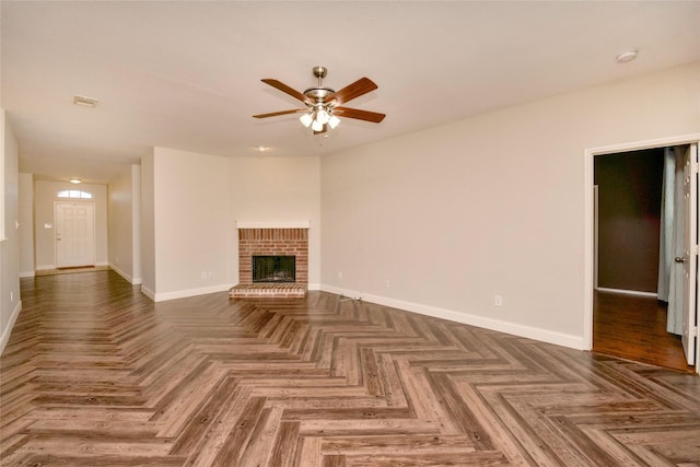 unfurnished living room featuring ceiling fan, dark parquet flooring, and a fireplace