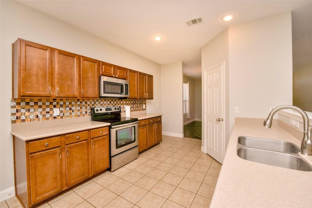 kitchen featuring decorative backsplash, light tile patterned floors, stainless steel appliances, and sink