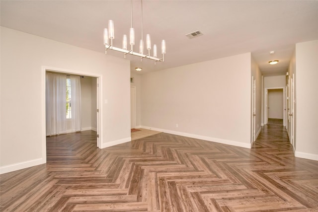 spare room featuring dark parquet floors and an inviting chandelier