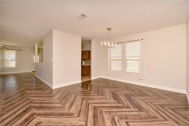 interior space with a notable chandelier, dark parquet floors, and plenty of natural light