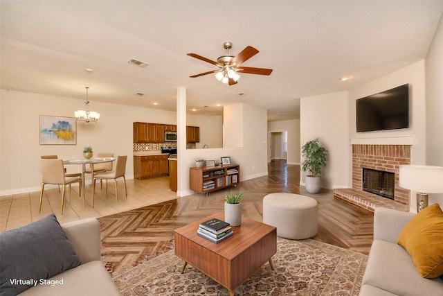 living room featuring a fireplace, light tile patterned floors, and ceiling fan with notable chandelier